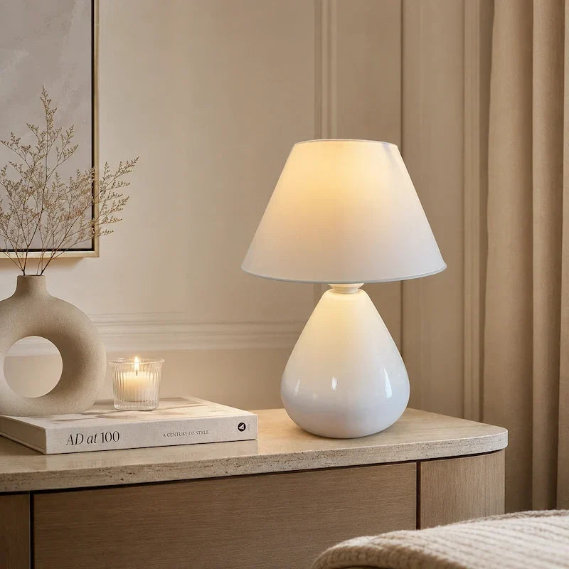 abajur de cerâmica branco em cômoda com vela
