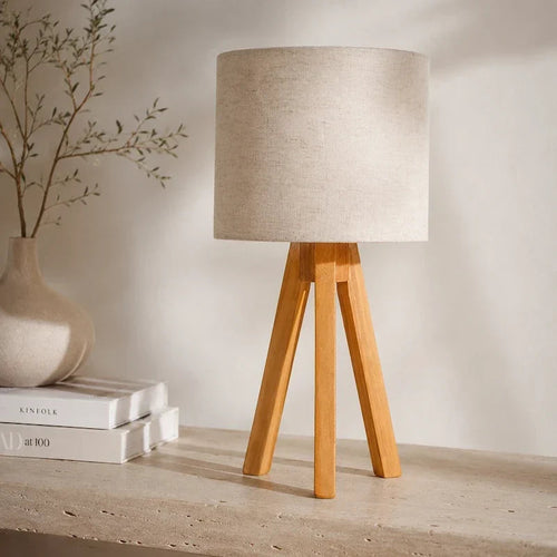 luminária de mesa tripé de madeira com cúpula de linho claro em ambiente decorado