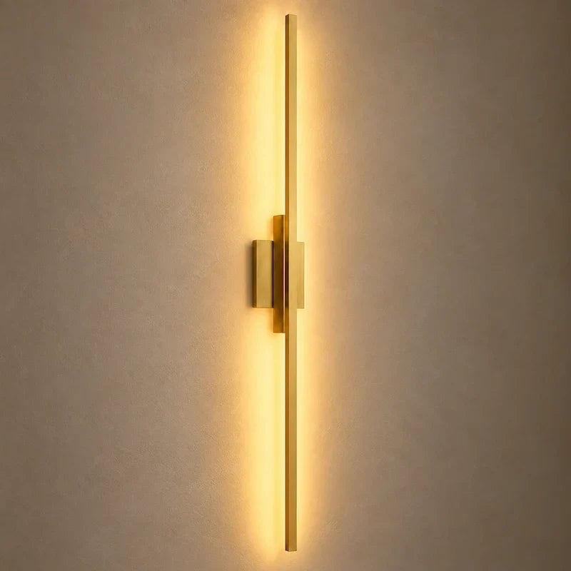 arandela led linear dourada acesa na parede com luz branco quente