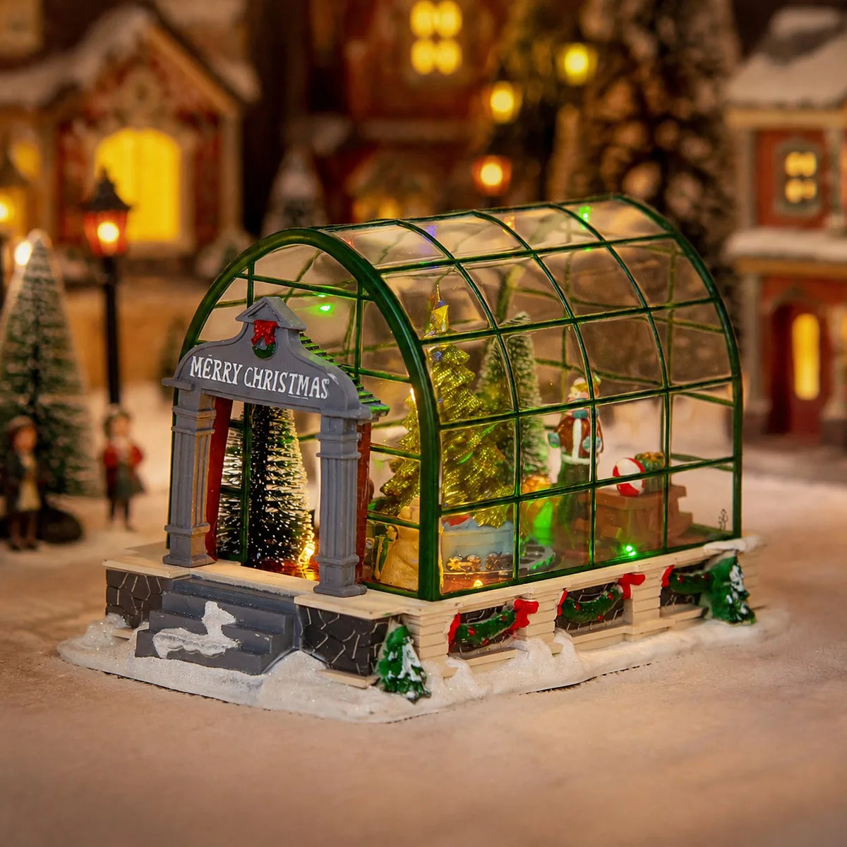 estufa iluminada compondo vila de natal em miniatura