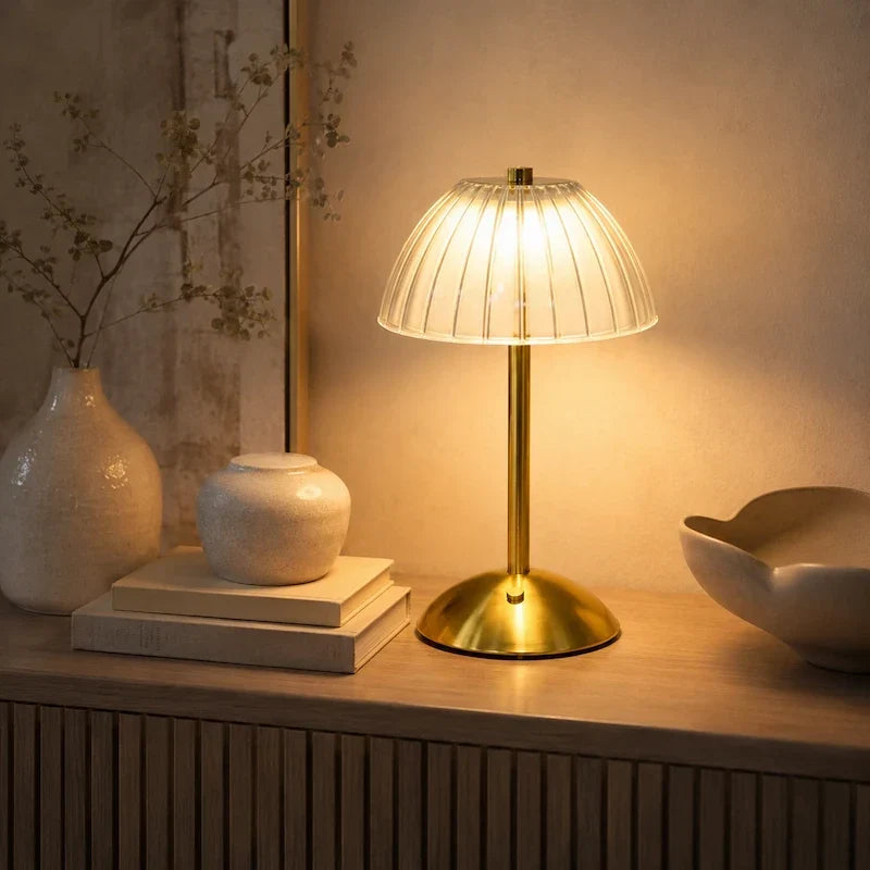 luminária de mesa dourada com cúpula translúcida canelada em destaque