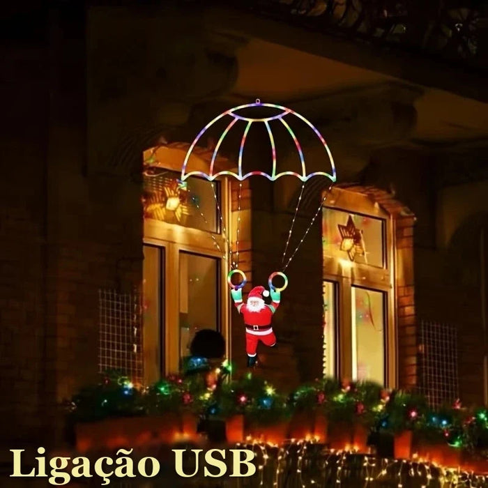 papai noel de paraquedas com luz led colorida na janela a noite